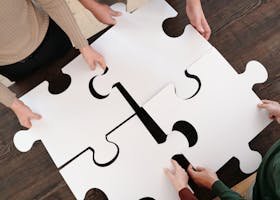 Group collaborating on assembling large puzzle pieces symbolizing teamwork and unity.